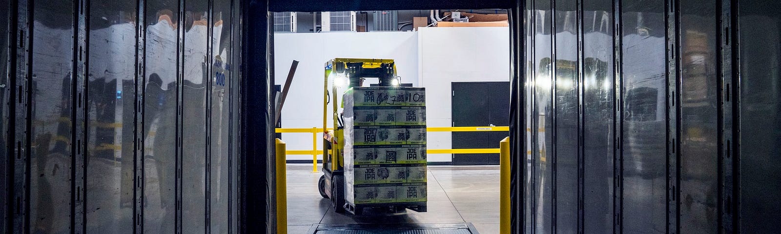 a forklift driving boxes into the back of a truck. Perspective from inside the truck
