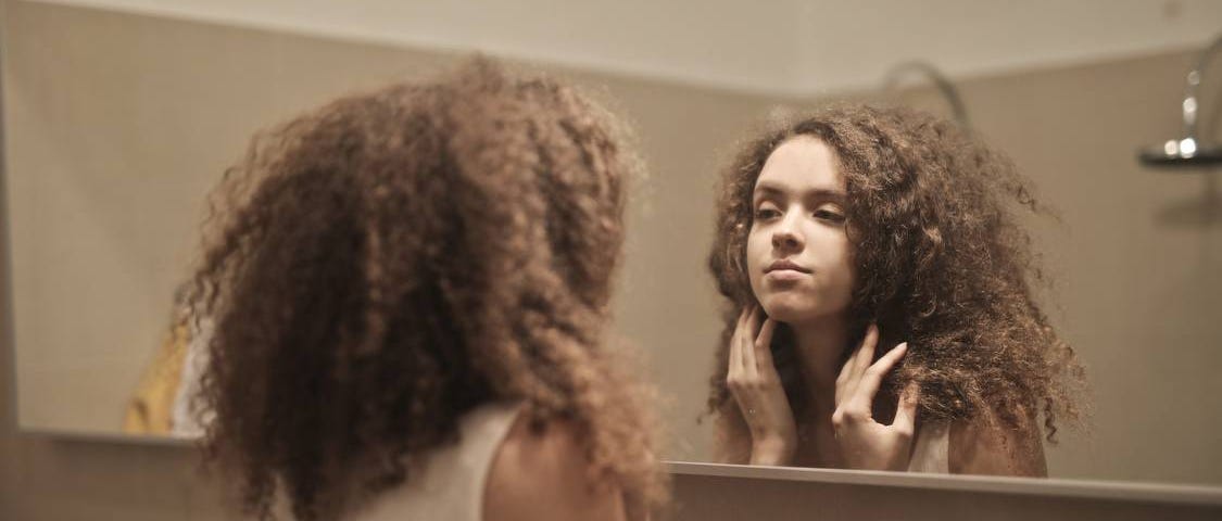 A photo of a woman staring back at herself in the mirror.