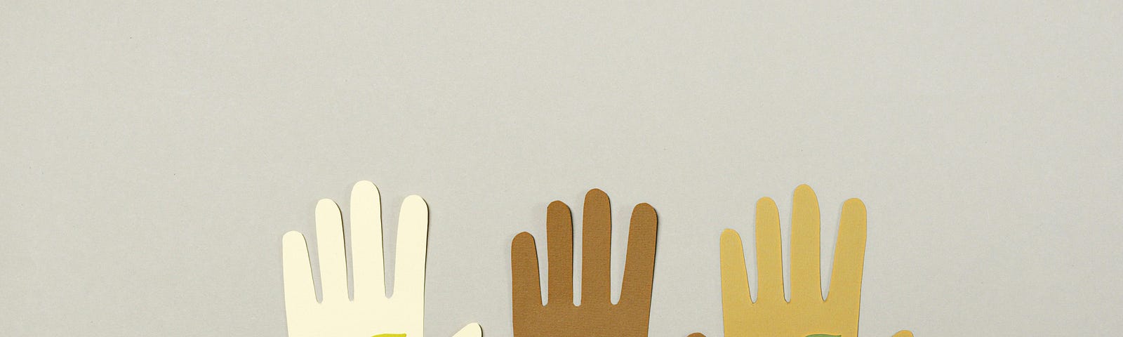 Paper cutouts of three hands in different skin tones with plants and a heart in the palms.