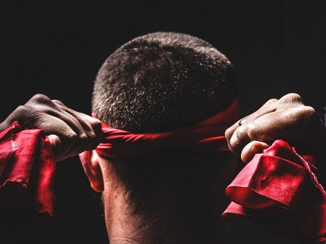 The back of the head of a man tying the red karate headband