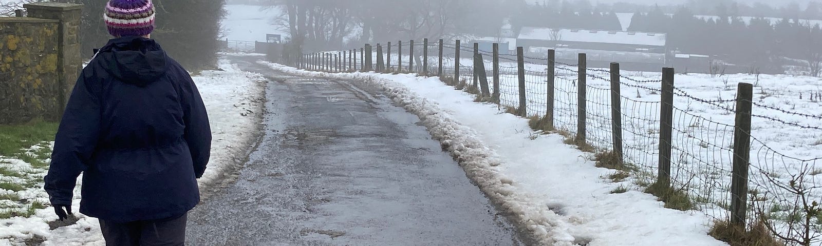 A woman walks down a hill in the snow.