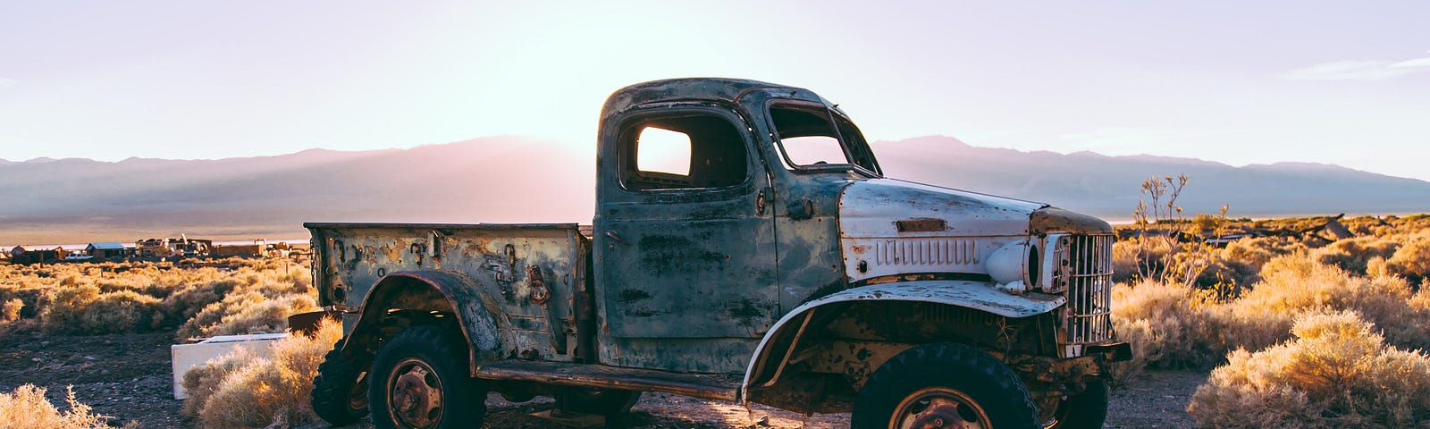 Antique pic up truck against a desert mountain sunset