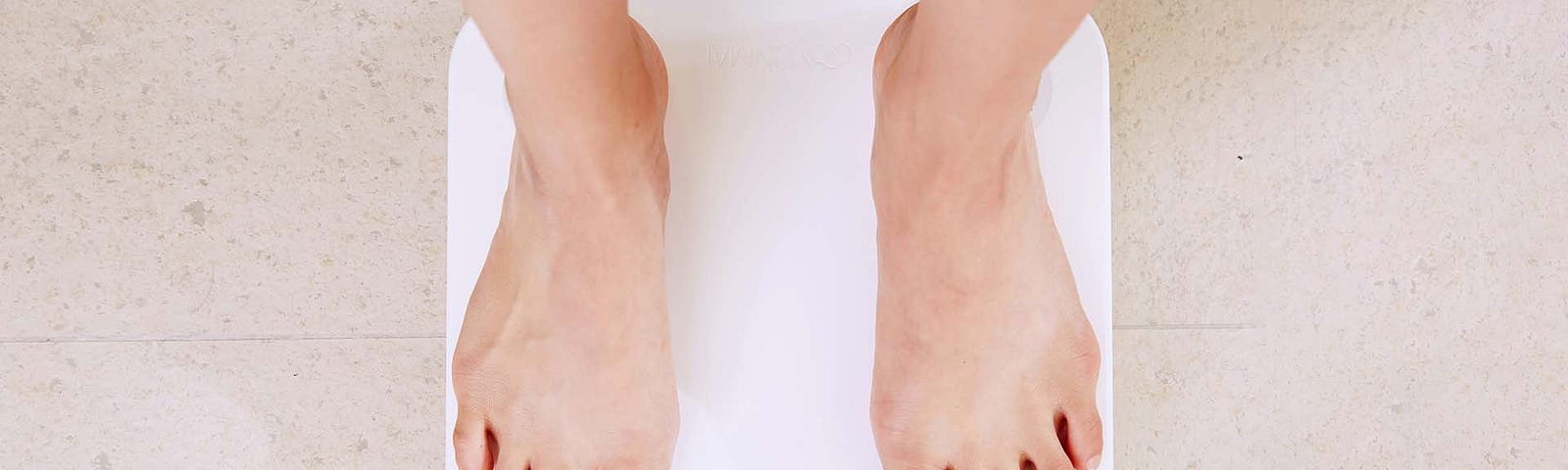 Looking down at a person’s feet on a scale.