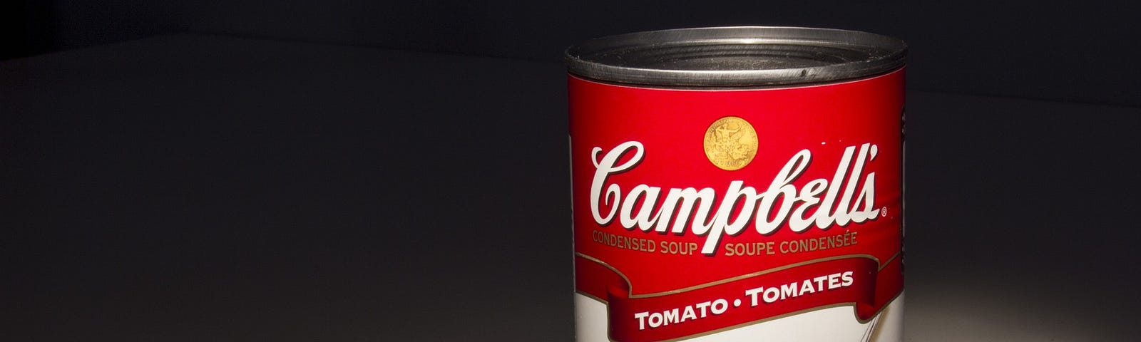 Can of Campbell’s tomato soup with a spotlight on it.