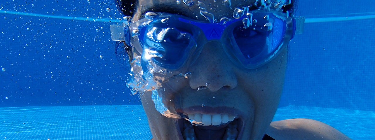 A woman underwater and wearing goggles screams