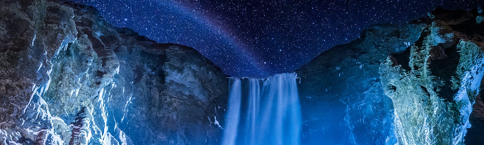 Waterfall at night beneath the starry sky.
