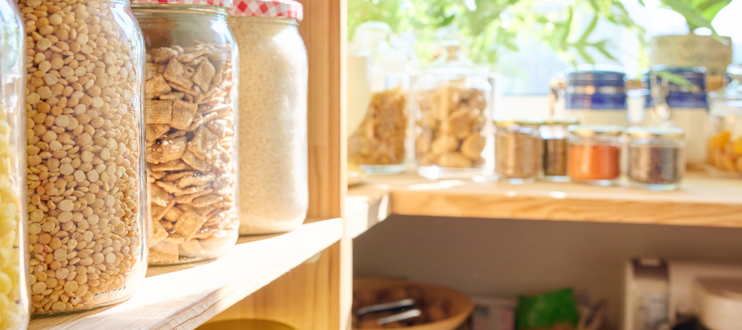 Pantry filled with dried goods and a bowl of apples with lots of light and space.