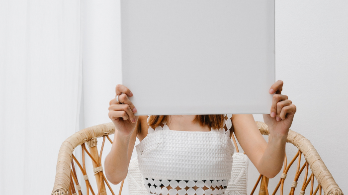 a girl covering her face with a white canvas