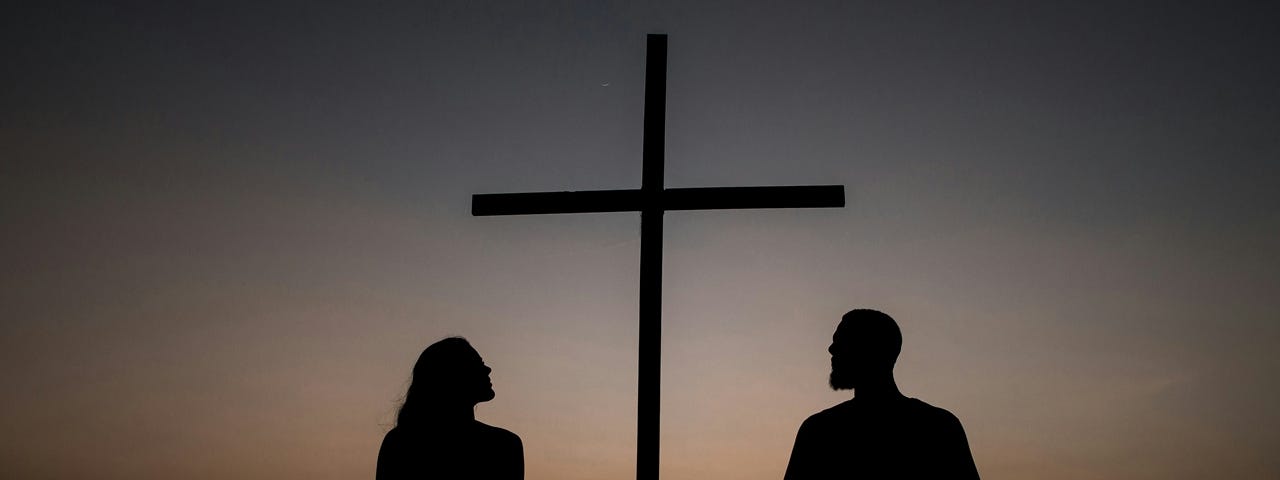 Two people looking at a cross