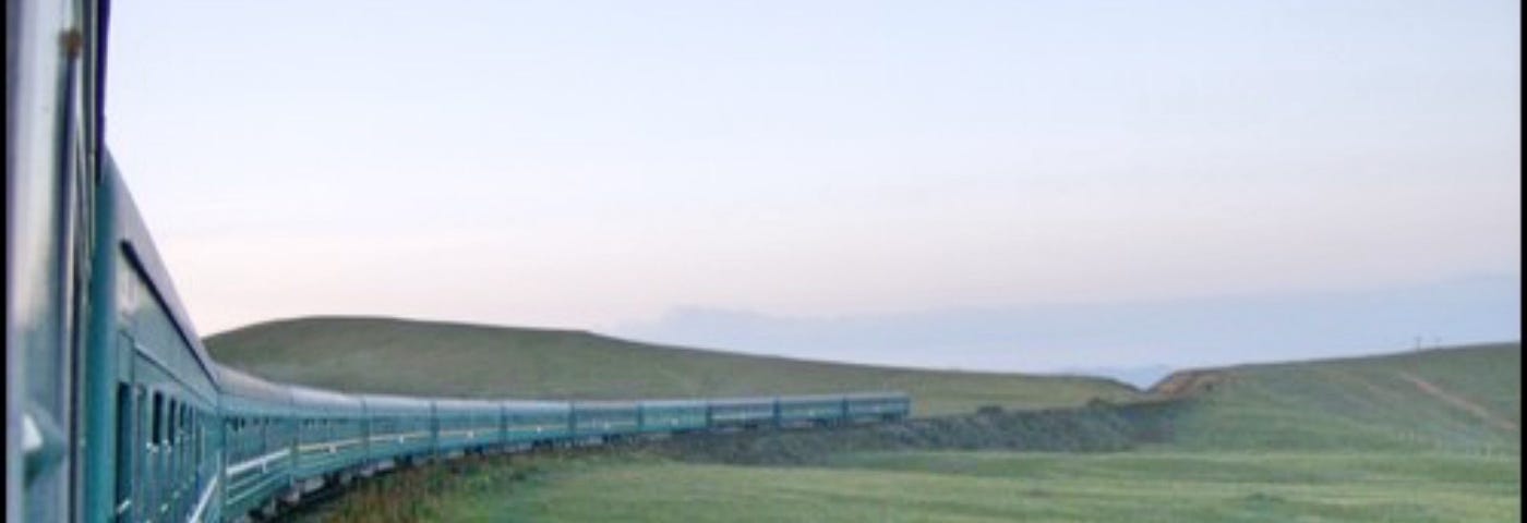 Train in a green landscape. Blue grey skies.