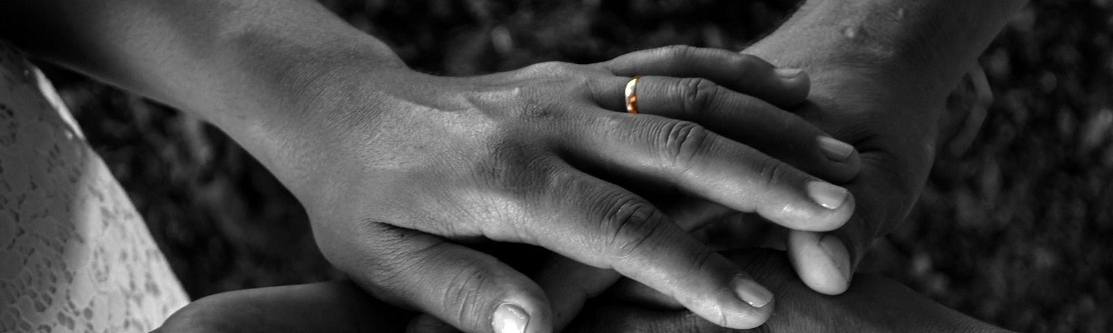 Hands coming together in a gesture of marriage with rings on wedding fingers.