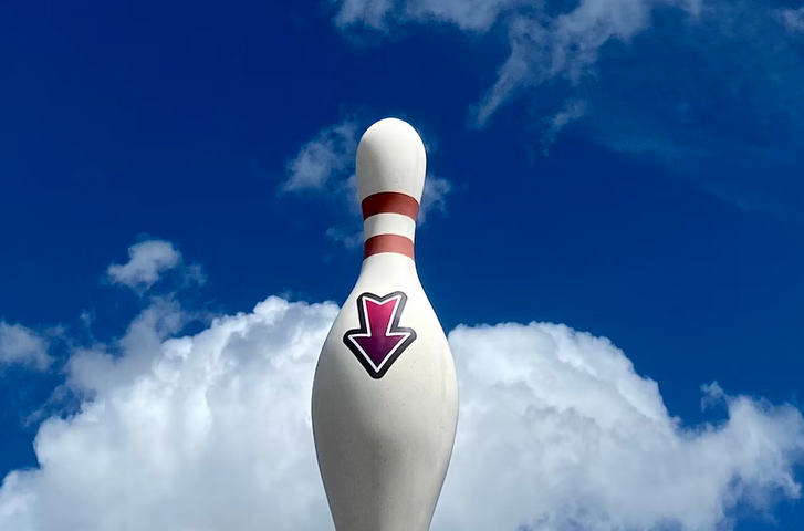 bowling pin against blue sky with white clouds