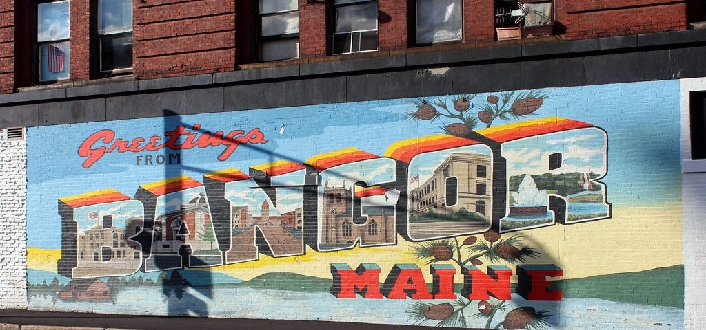 Greetings from Bangor, Maine painted on the side of a brick building.