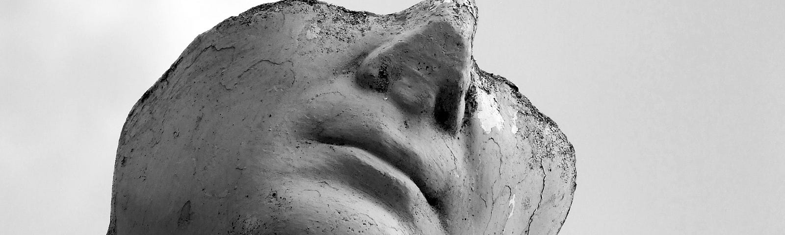 Photo from under Roman statue looking downward with head severed from eyes up and surface on cheek eroding.