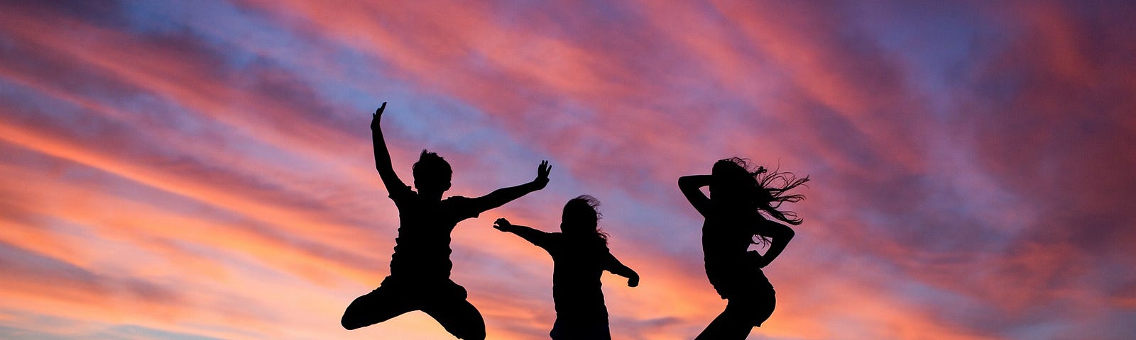 A group of three people jumping agains the sunset