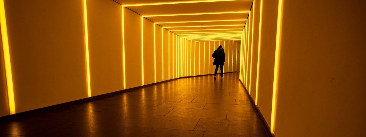 Distant silhouette of a man walking into a neon-lighted tunnel. (Use AI Wisely)
