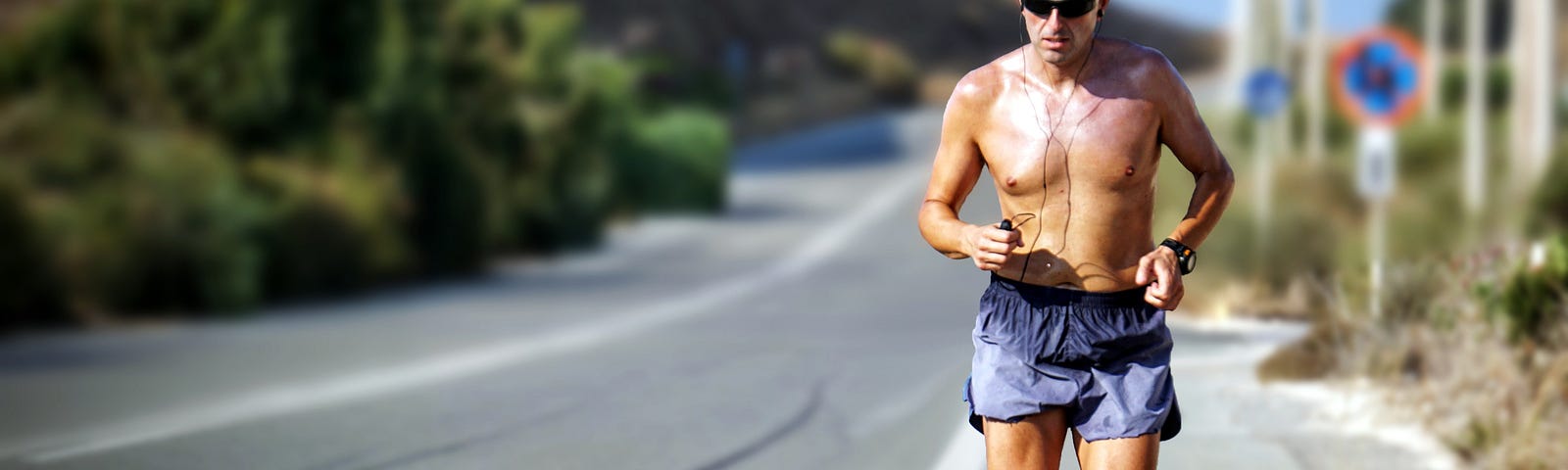 Male runner, topless, on a quiet country road.