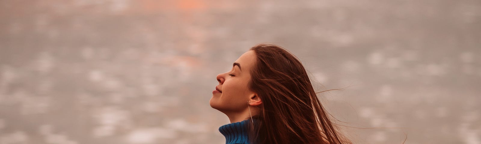 Young woman with eyes closed on windy beach