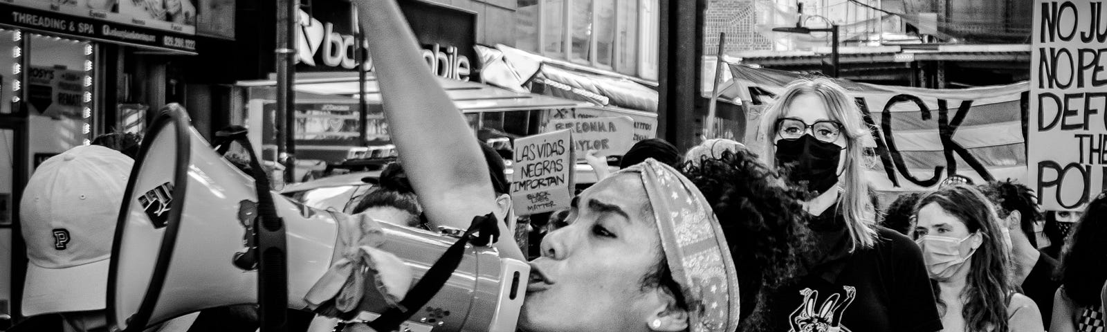 A woman chants into a megaphone at a Defund the Police protest.