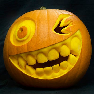 Photo of a carved pumpkin with a winking eye and big teeth.