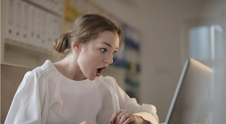 Woman in front of a computer. Her mouth is open.