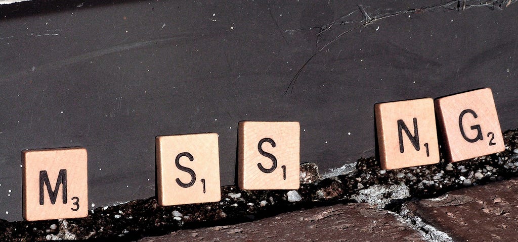 Scrabble tiles seemingly spelling out the word “MISSING,” though the two “I” tiles are missing.