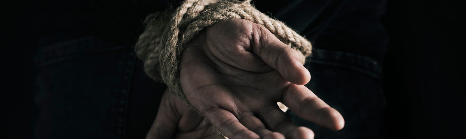 A man’s hands tied behind his back.