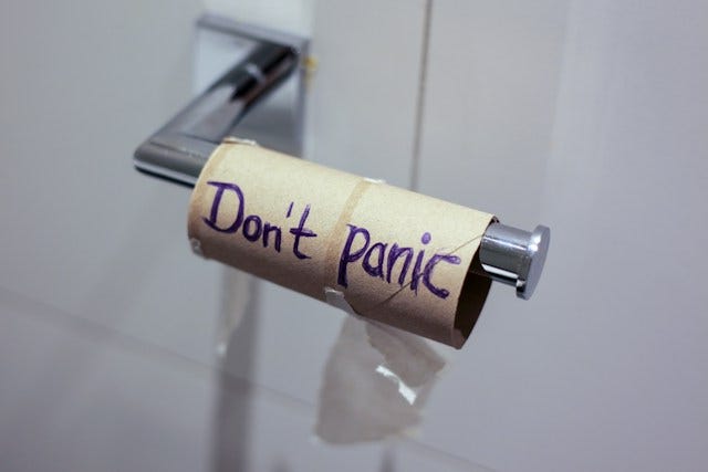 Toilet roll holder with only the cardboard roll and it says “don’t panic.”