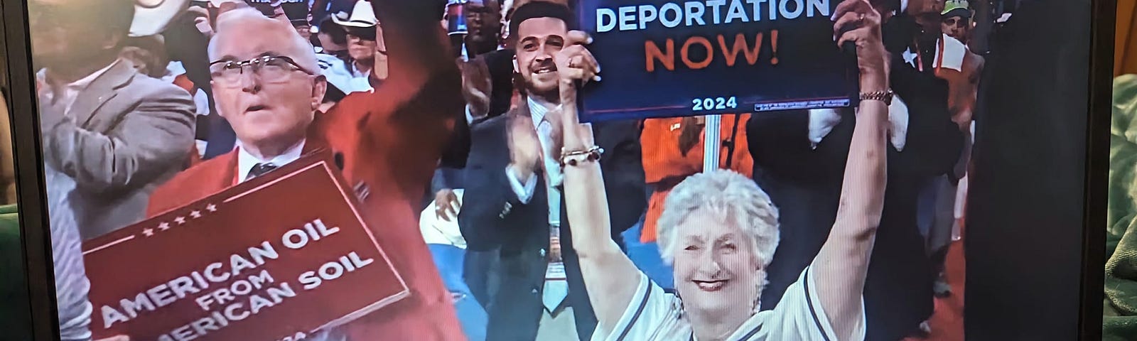 Photo of computer screen during the 2024 RNC convention: elderly man stands in a red sports coat, his fist in the air as he holds a sign that reads, “American Oil from American Soil.” Seated next to him is an elderly woman with short, gray hair, red lipstick, wearing an Alabama baseball jersey; her sign reads, “Mass Deportation NOW!”