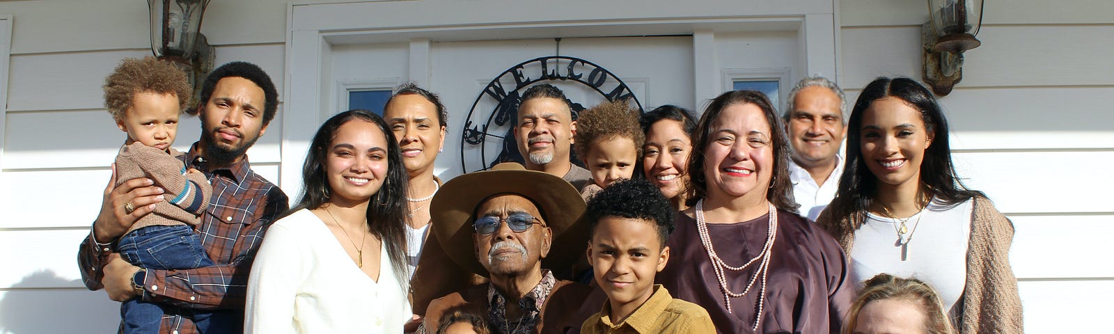 Mixed family with adults and kids standing in front of a home.
