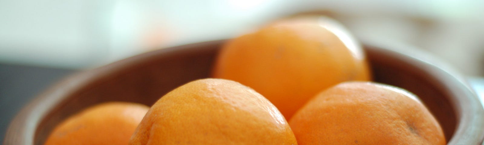 A wooden bowl of oranges.