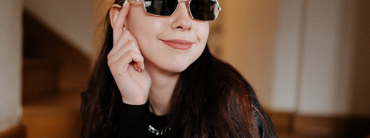 A woman dressed all in black wearing sunglasses.