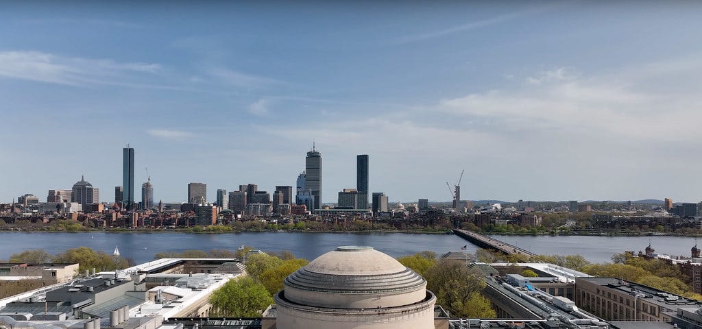 Aerial view of MIT’s Great Dome with the Charles River and Boston skyline in the background.