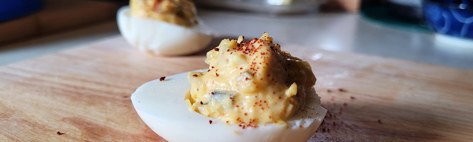 Close up of a deviled egg on a wooden cutting board