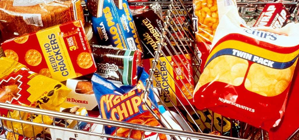 IMAGE: A shoipping cart filled with all sorts of ultra-processed foods and snacks