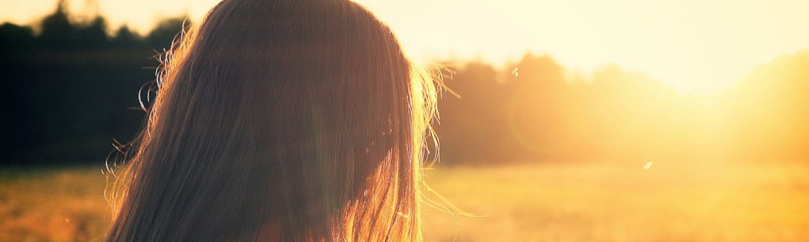 A long-haired figure in the sunshine, looking away