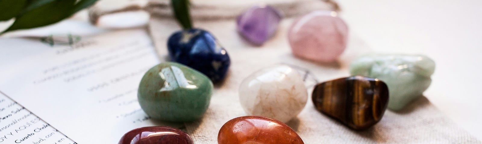 9 stones colored blue, brown, green, red, black, pink, purple and yellow laying on a table