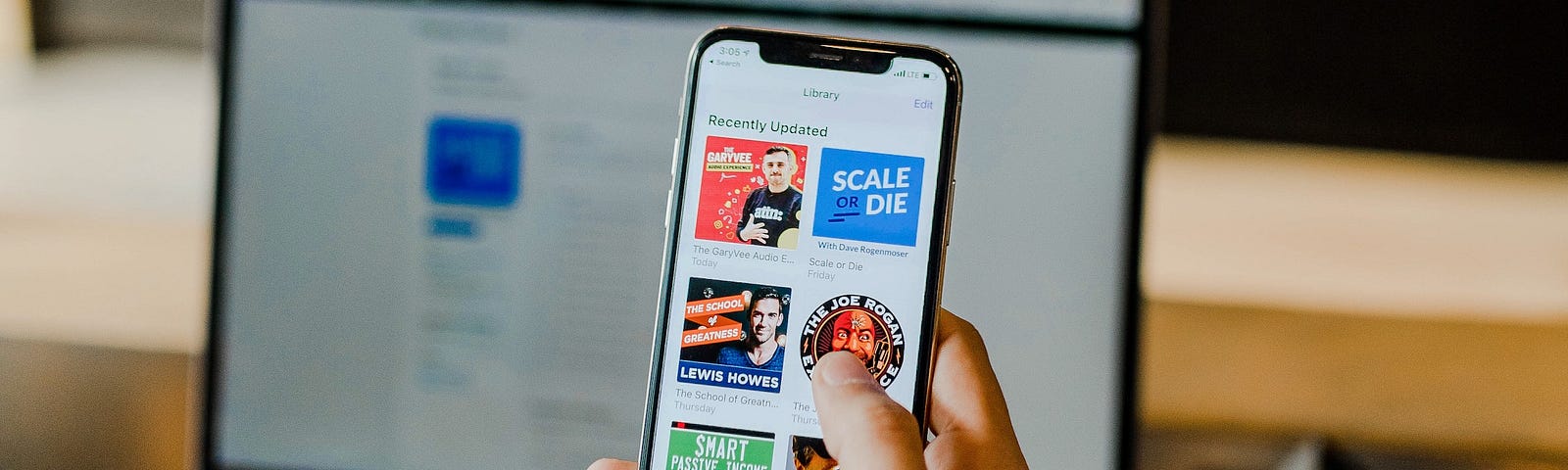 Person holding a phone with several icons of podcasts avaialble for listening.