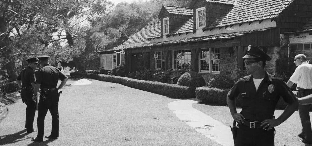 Policemen stand outside the Hollywood home of Roman Polanski and Sharon Tate at 10050 Cielo Drive now a crime scene