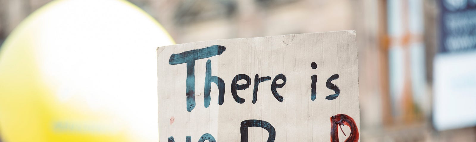 A hand holds up a sign that says THere is NO Planet B