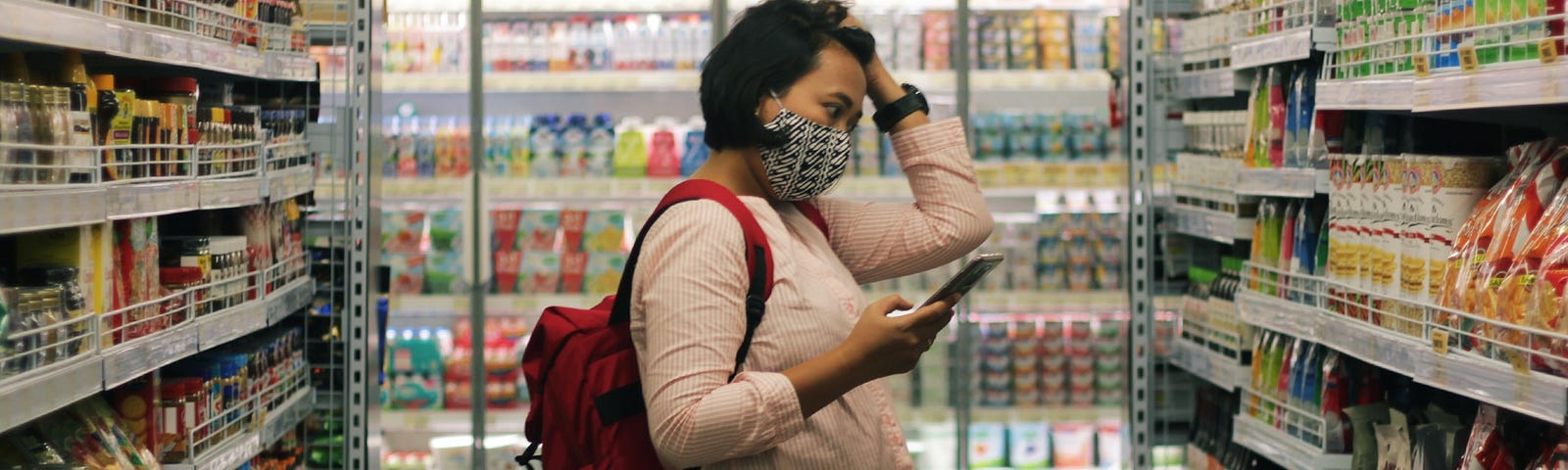 A woman checking grocery stores shelving product.