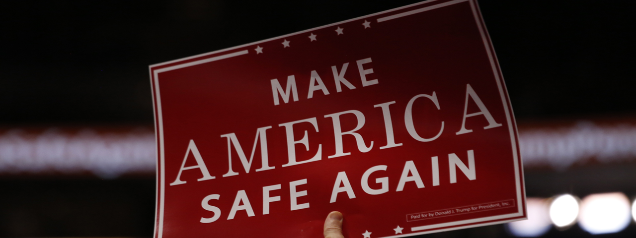 Hand holding up a sign: Make America Safe Again