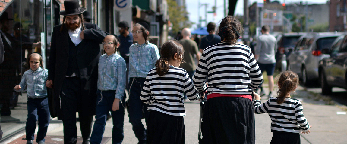 Two Hasidic families walk in opposite directions on a NYC street