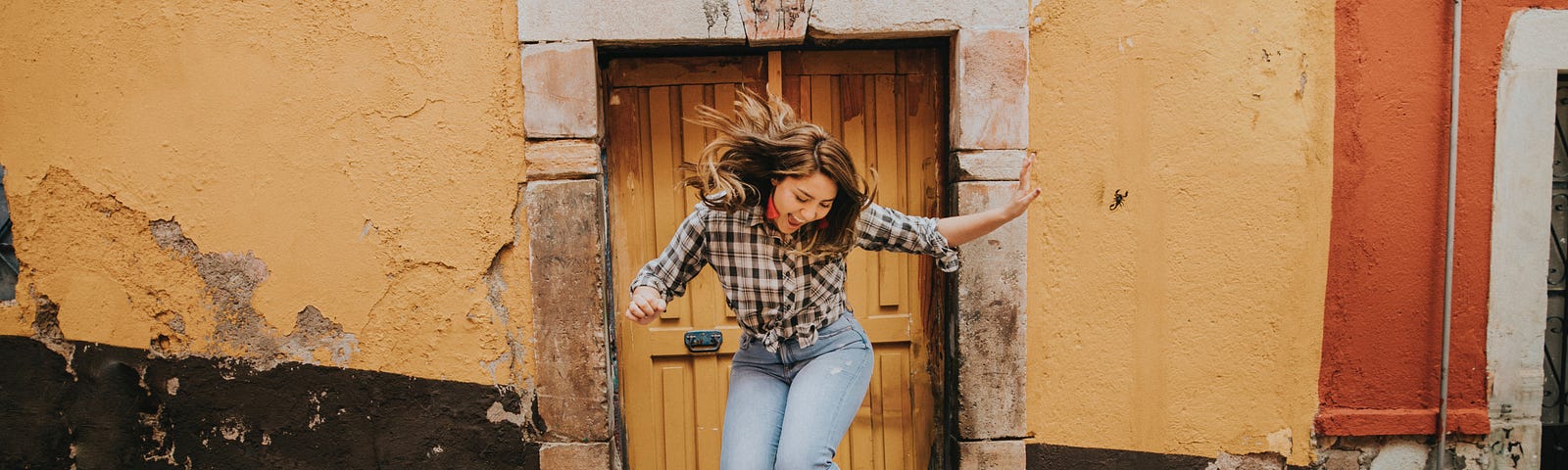 Woman jumping out of joy in front of the door of an old house