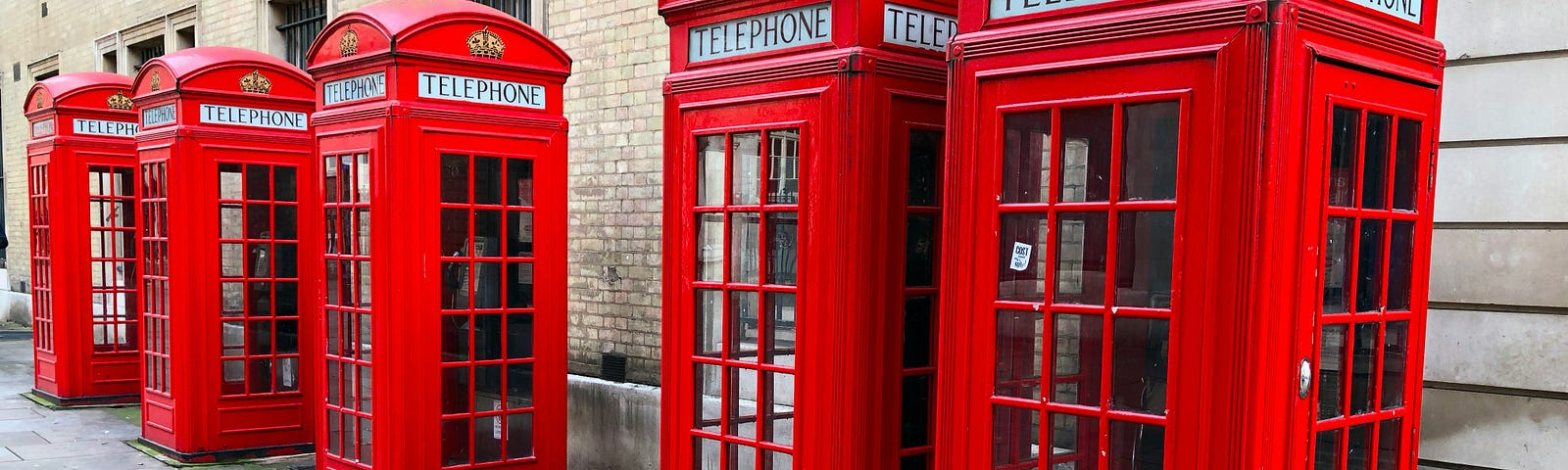 A row of typical English red public phone booths along a street