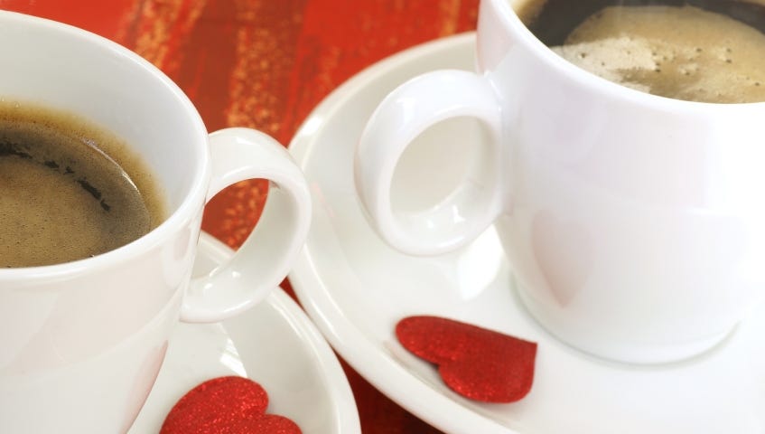 Two cups and saucers with coffee and a red hear on each saucer