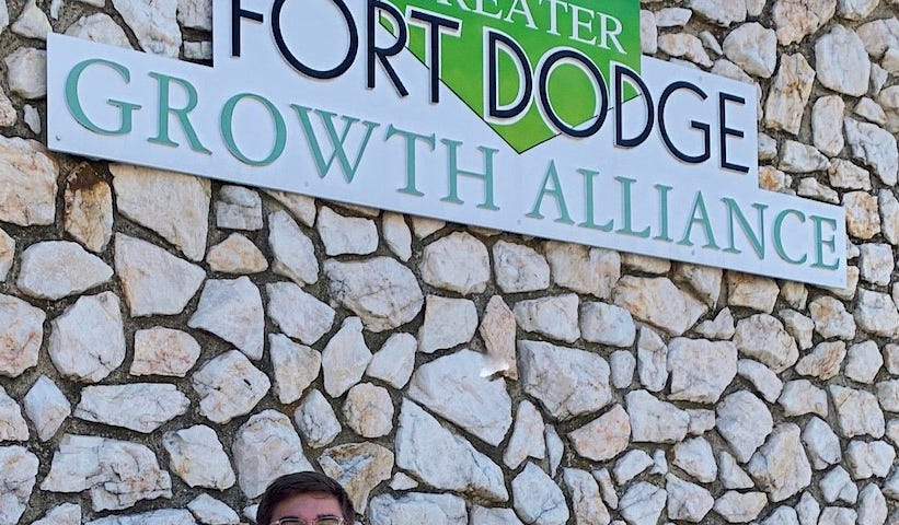 Keaton Dornath, a business analytics and marketing junior, stands in front of a Greater Fort Dodge Growth Alliance sign.