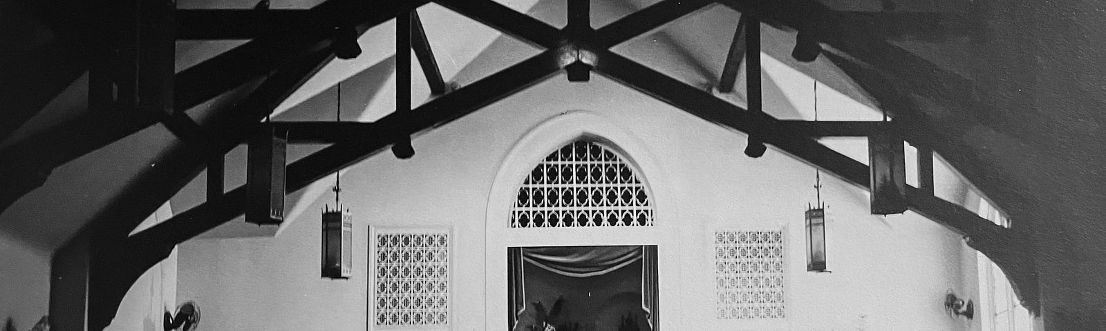 Vintage black and white photo of wedding from back of church bride and groom at the end of center aisle flanked by best man, father of bride and maid of honor.