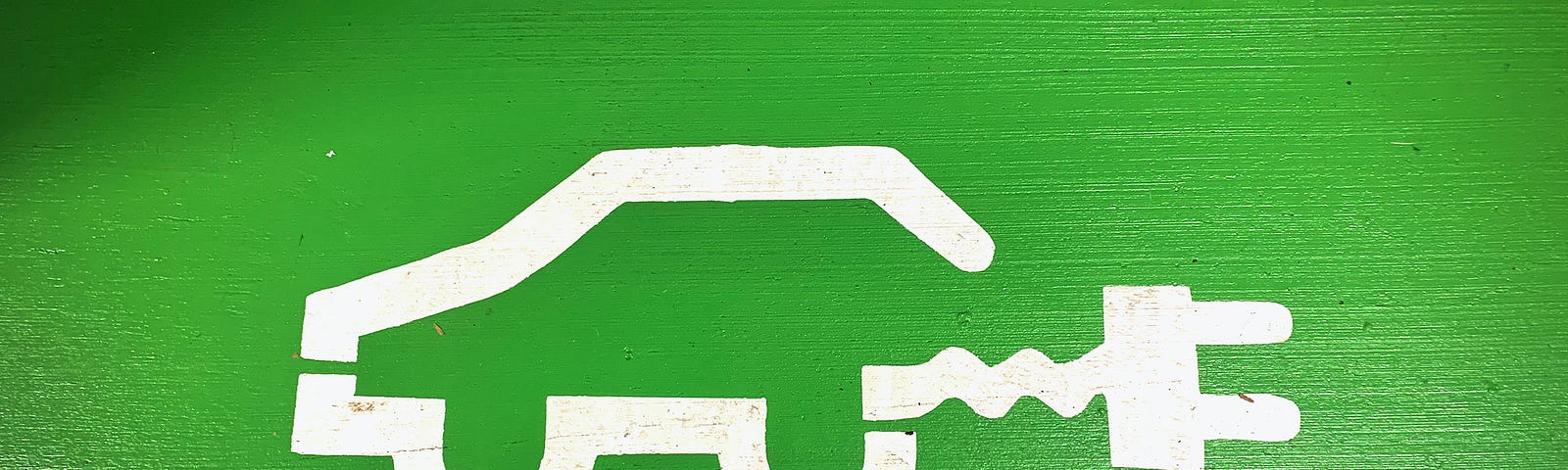 A green-painted parking space featuring a symbol of an electric vehicle.