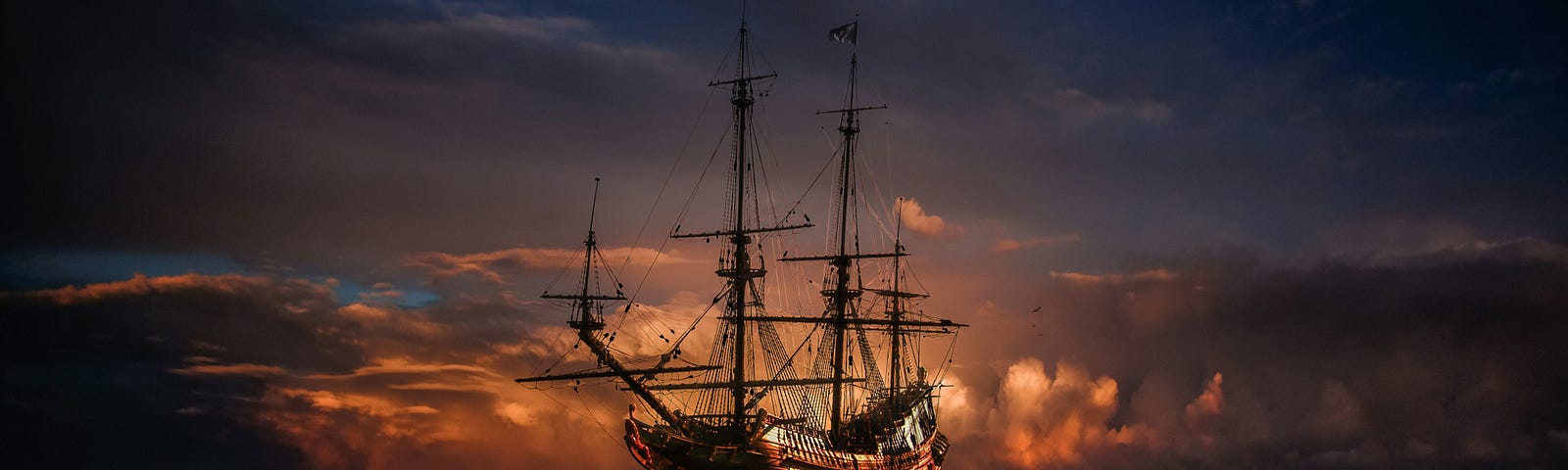 A pirate ship at sea with a darkening sky and sunlit clouds reflecting on the water.